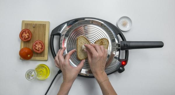 Set Navigenio to low level, place 2 slices of bread in the oPan and roast on one side. Turn and rub bread with tomato and garlic.