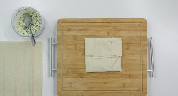 Place 2 sheets of yufka dough on top of each other and spread some Feta mixture on top. Fold the top and bottom sides in the middle. Fold over the right side, lay the left side over it and fix it with a little water.