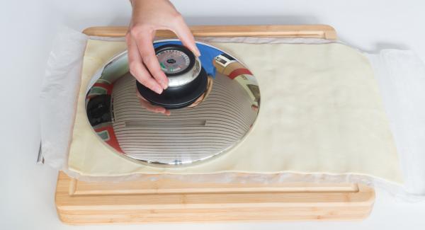 Cut out a round dough sheet with the help of a lid 24 cm.