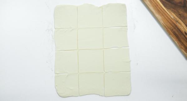 Roll out the puff pastry on a floured work surface and cut into twelve squares of 10 x 10 cm.